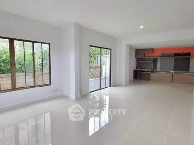 Spacious open-plan living area with large windows and modern kitchen.