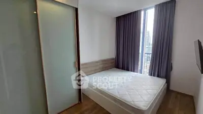 Modern bedroom with large window and city view, featuring a minimalist design and ample natural light.