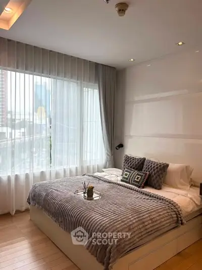 Modern bedroom with large window and stylish decor in urban apartment.