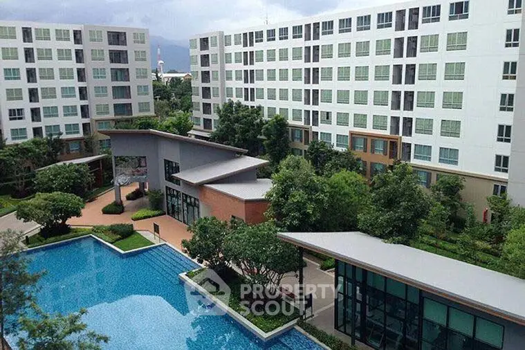 Modern apartment complex with pool and lush greenery, offering serene living environment.