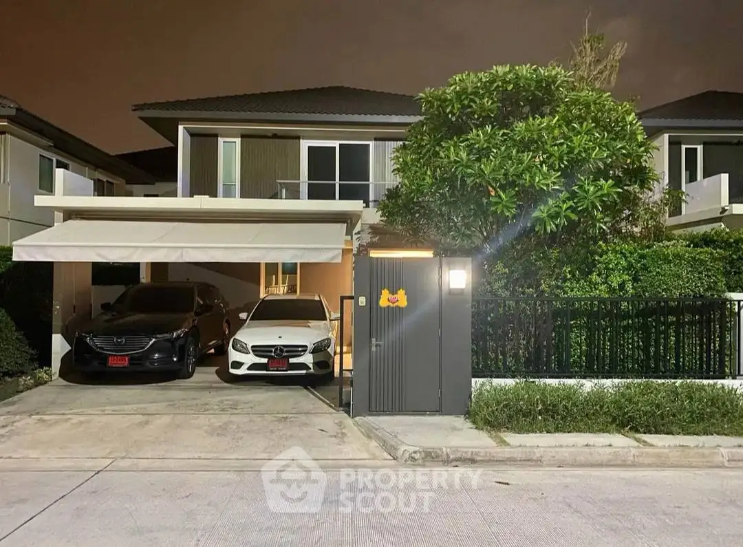 Modern two-story house with carport and lush greenery in a serene neighborhood.