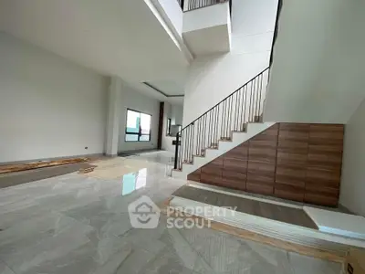 Spacious modern interior with elegant staircase and large windows in a contemporary home.