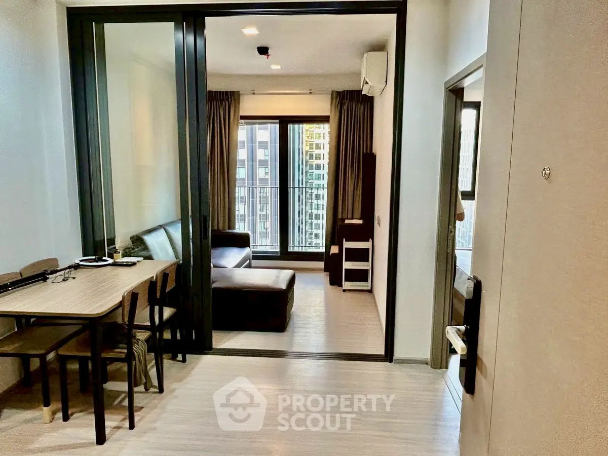 Modern apartment with open living room and dining area, featuring large windows and stylish furnishings.