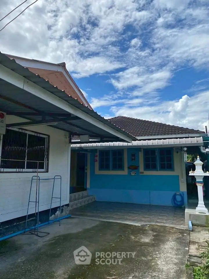 Charming single-story home with blue accents and spacious driveway under a clear sky.