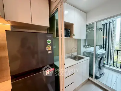 Modern kitchen with sleek appliances and laundry area in a high-rise apartment.