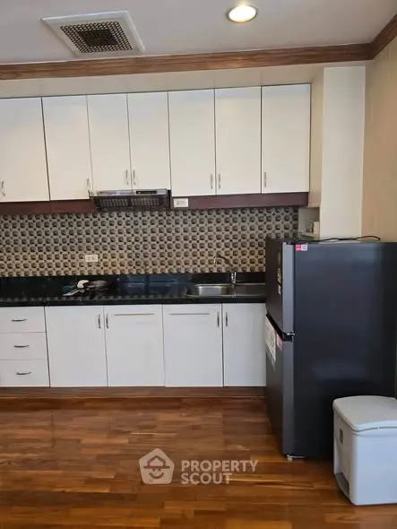 Modern kitchen with sleek cabinets and stainless steel fridge in a stylish apartment.