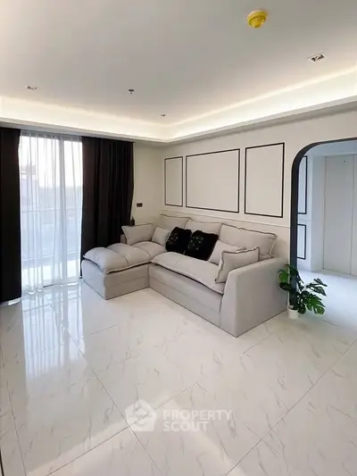 Spacious modern living room with elegant sofa and large windows for natural light.