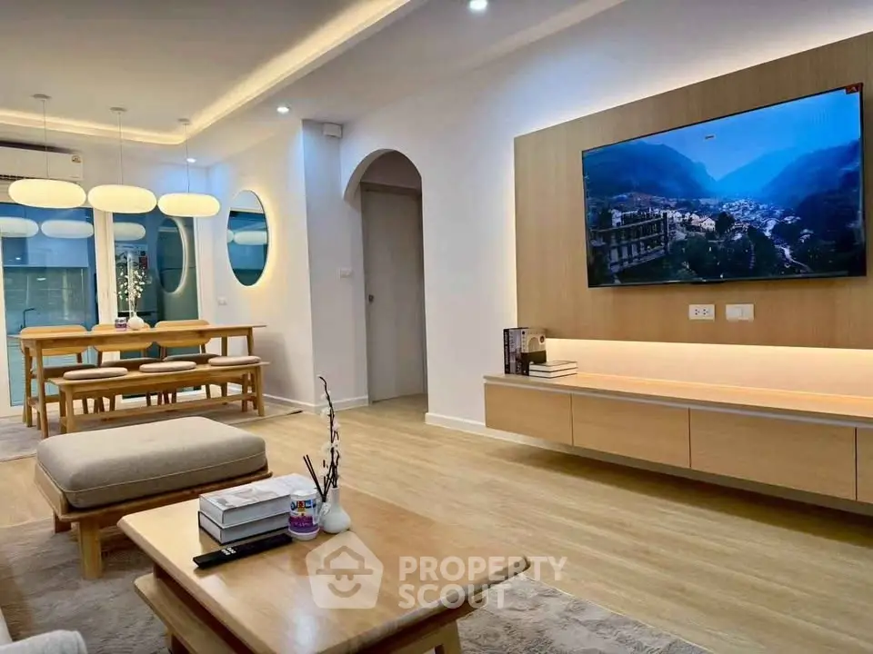 Modern living room with stylish decor and wall-mounted TV, featuring elegant dining area and cozy seating.