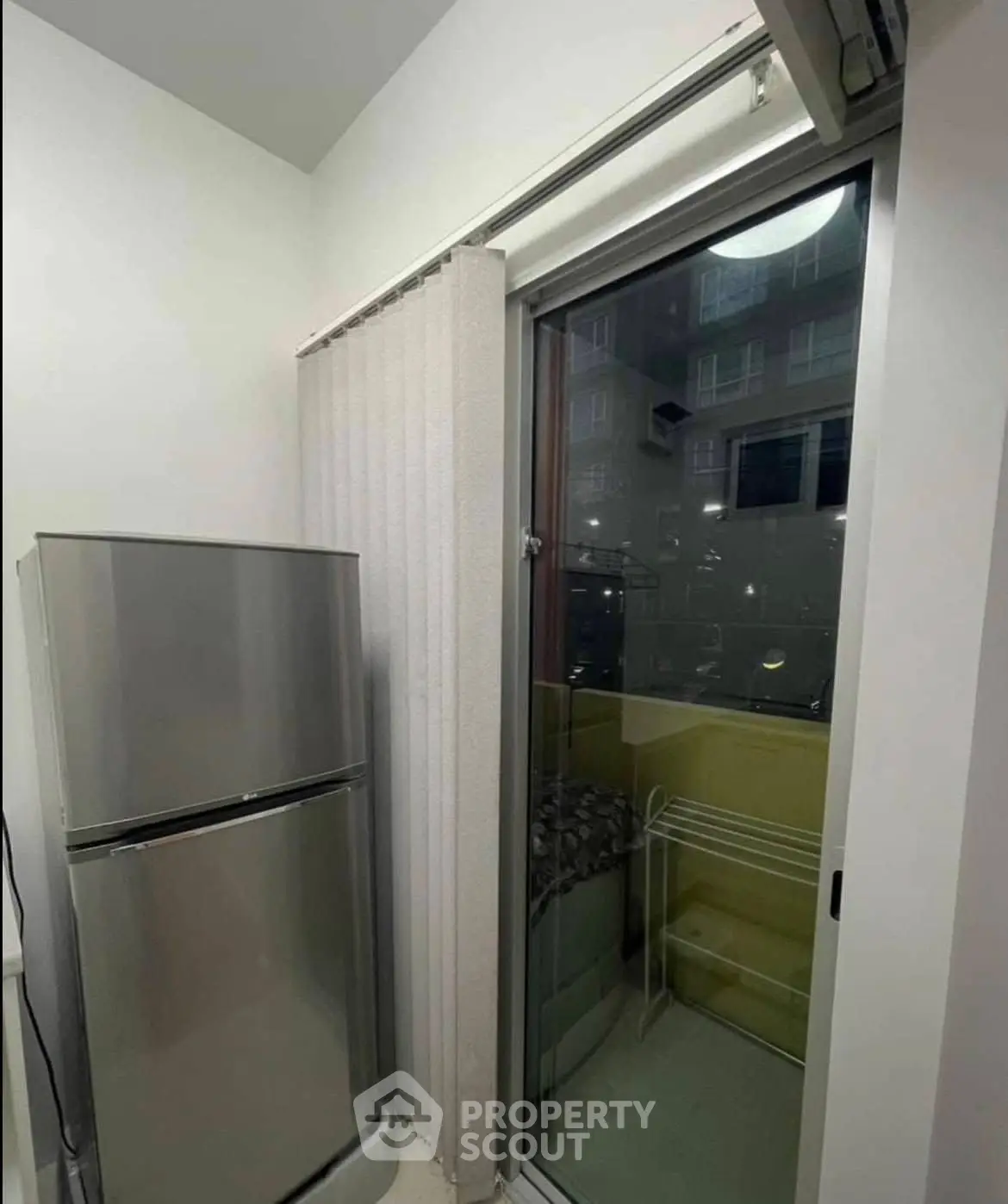 Compact kitchen area with fridge and balcony access in modern apartment