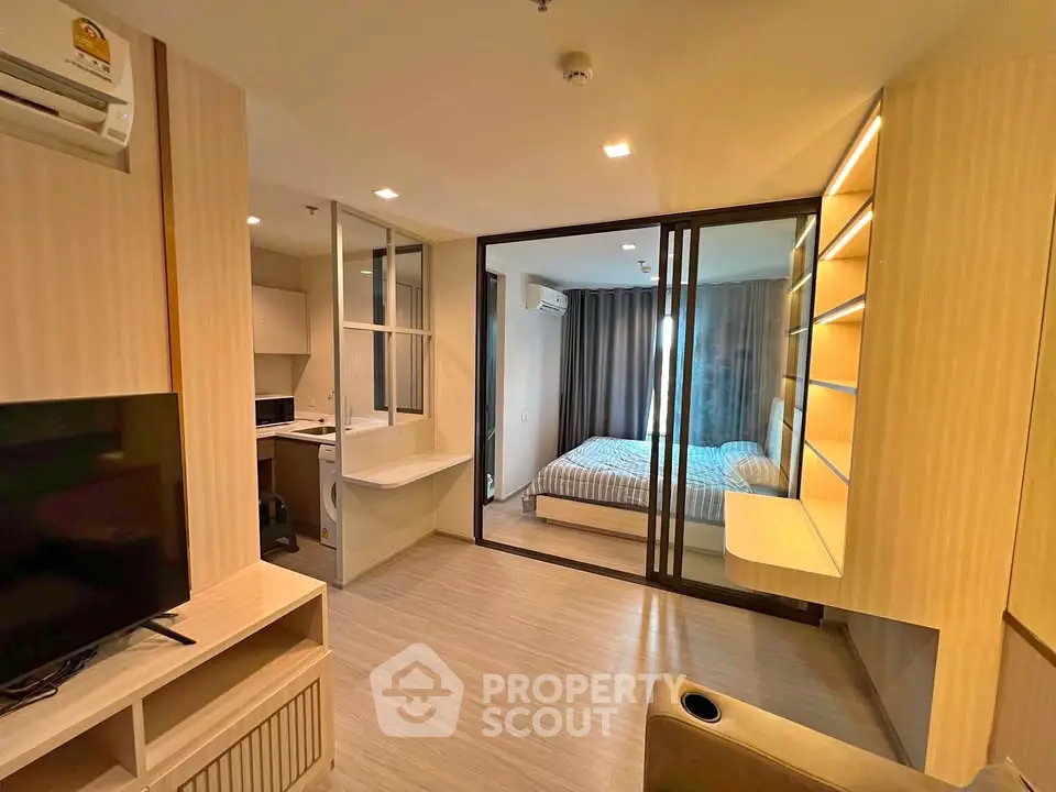 Modern apartment interior with cozy living room and bedroom separated by glass doors, featuring sleek design and warm lighting.