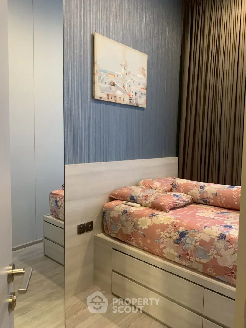 Cozy bedroom with floral bedding and modern decor, featuring a large mirror and stylish artwork.