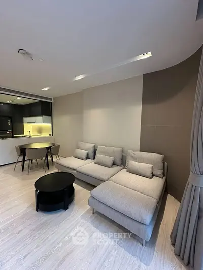 Modern living room with sleek furniture and open kitchen layout in a stylish apartment.