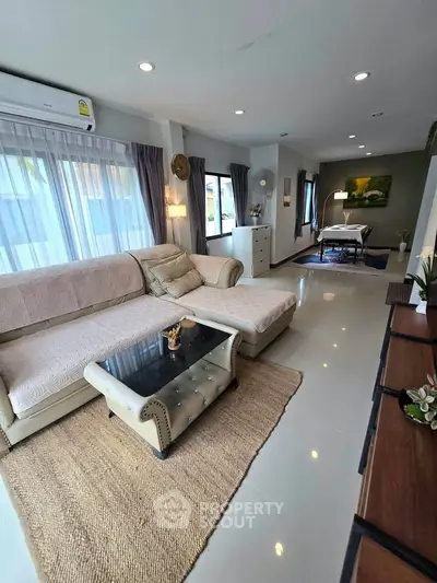 Spacious living room with elegant decor and natural light, featuring a cozy sectional sofa and modern dining area.