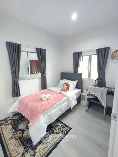 Cozy bedroom with single bed, plush decor, and ample natural light from two windows.
