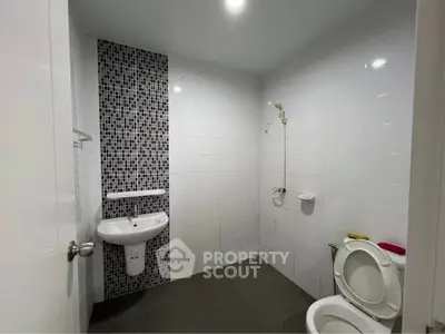 Modern bathroom with sleek design and mosaic tile accent wall.