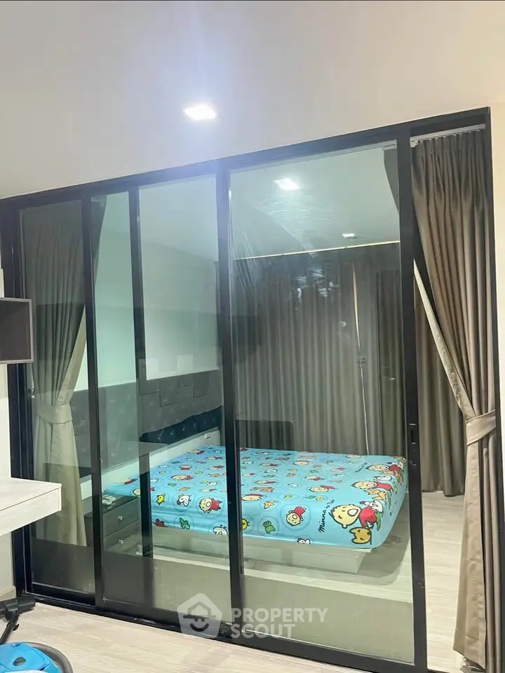 Modern bedroom with glass sliding doors and playful bedding in a stylish apartment.