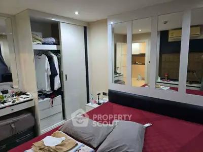 Cozy bedroom with mirrored wardrobe and red bedding in modern apartment