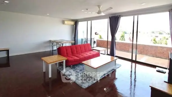 Spacious living room with red sofa and large balcony access