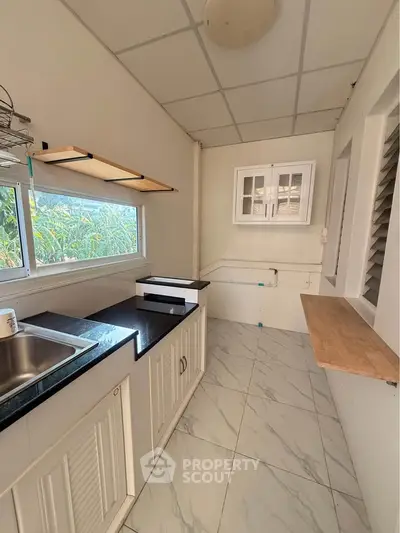 Charming kitchen with sleek countertops and ample natural light, perfect for culinary enthusiasts.