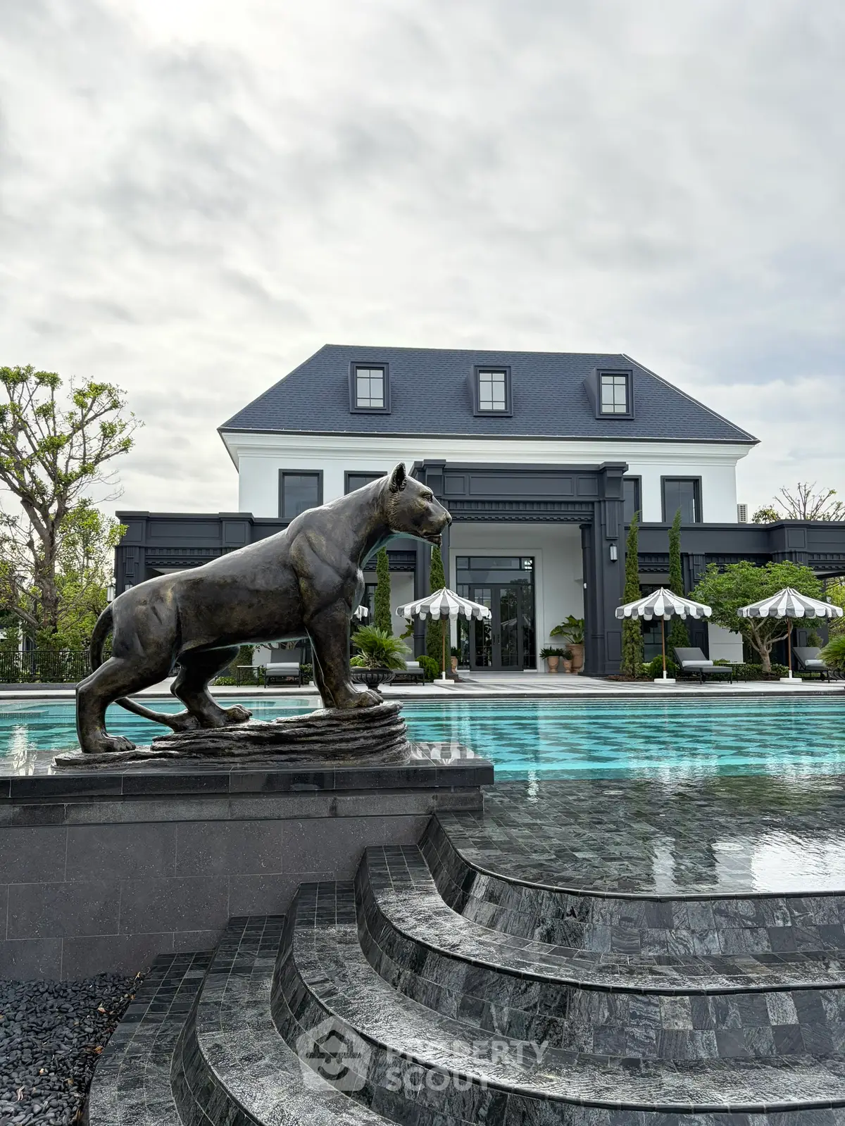 Luxurious mansion with elegant pool and stunning architecture, featuring a unique panther statue for a grand entrance.