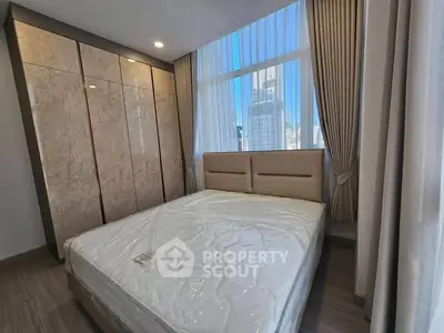 Modern bedroom with large windows and city view, featuring a stylish bed and built-in wardrobe.
