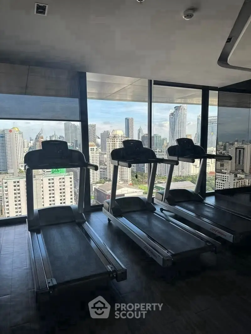 Modern gym with city view featuring treadmills and large windows.
