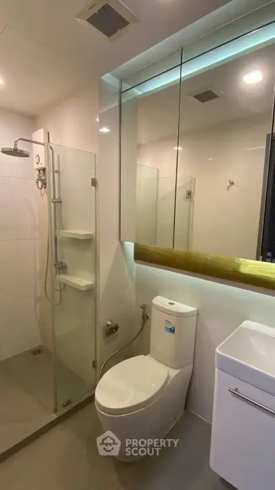 Modern bathroom with glass shower and sleek fixtures in contemporary apartment.