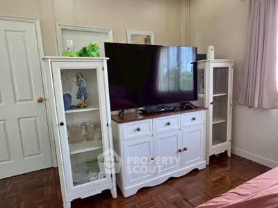 Charming bedroom with elegant white cabinets and a sleek TV setup, perfect for cozy relaxation.