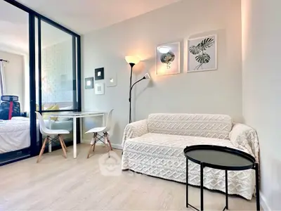 Modern living room with cozy sofa, stylish decor, and dining area in open layout apartment.
