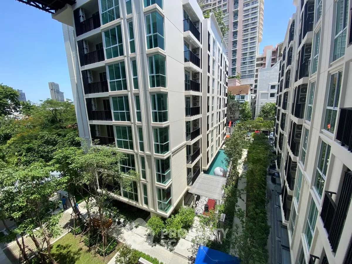 Modern apartment buildings with lush greenery and clear blue sky view.