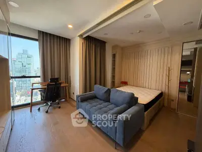 Modern studio apartment with city view, featuring a cozy sofa, bed, and work desk, ideal for urban living.