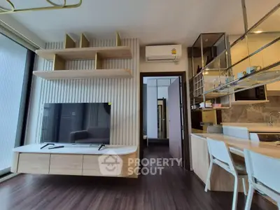 Modern living room with sleek TV unit and open kitchen layout in stylish apartment.