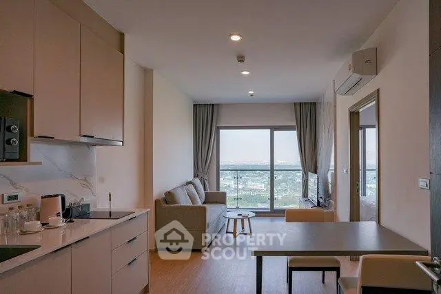 Modern open-layout living room with kitchen and scenic view, featuring sleek furniture and natural light.