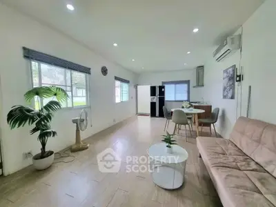 Spacious living room with modern decor and natural light, featuring a cozy sofa and dining area.