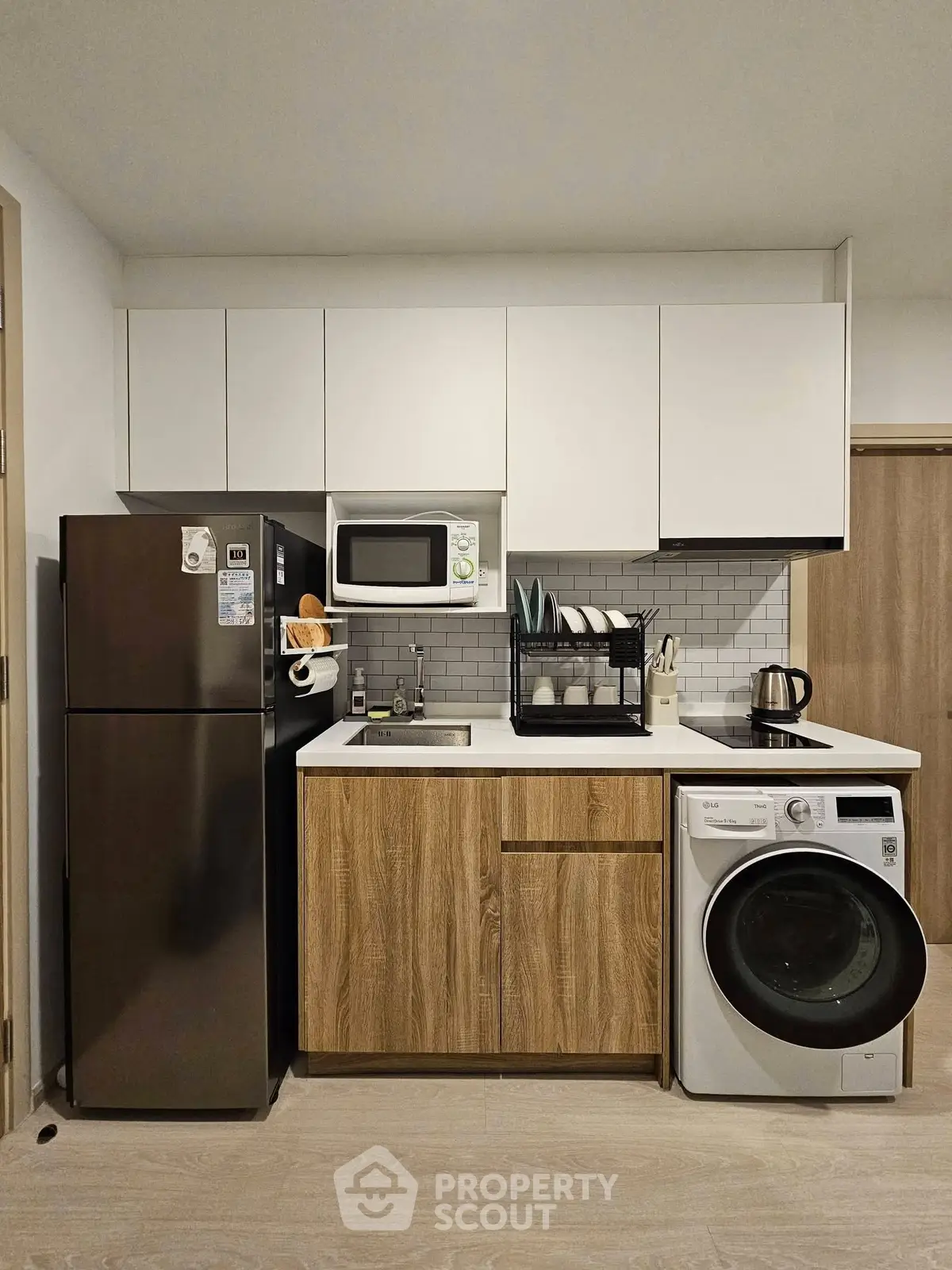 Modern compact kitchen with washing machine and microwave in stylish apartment
