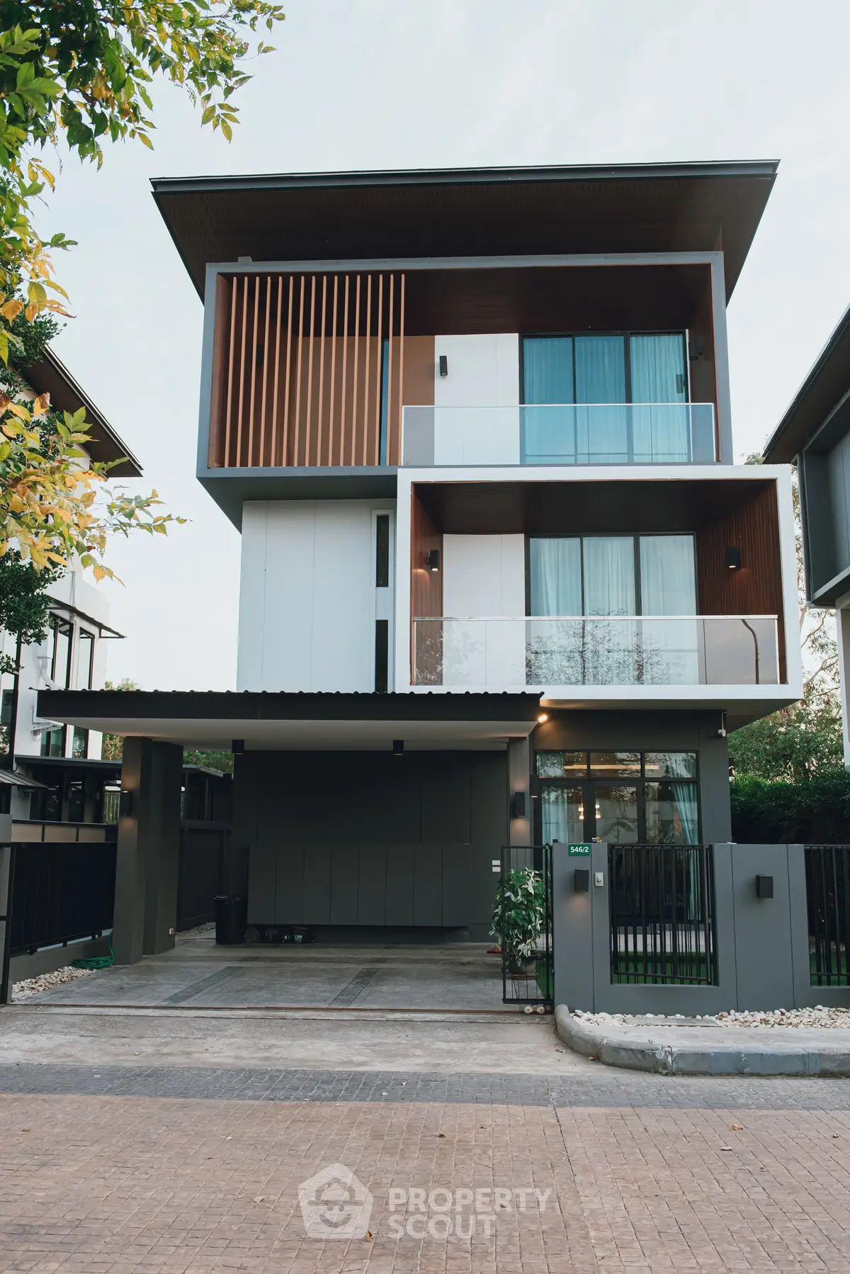 Modern three-story house with sleek design and large windows in a suburban neighborhood.