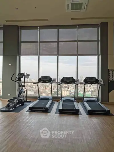 Spacious gym with modern equipment and panoramic city view, perfect for fitness enthusiasts.