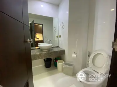 Modern bathroom with sleek white fixtures, wall-mounted mirror, and granite countertop, offering a clean and minimalist aesthetic.