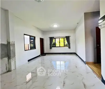 Spacious empty room with marble flooring and large windows for natural light.