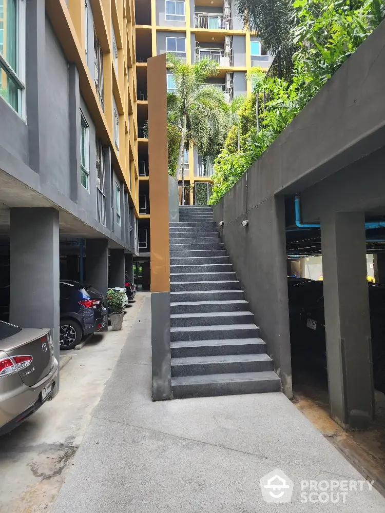 Secure parking area in a modern residential building with easy access stairs leading to a welcoming, lush green environment.