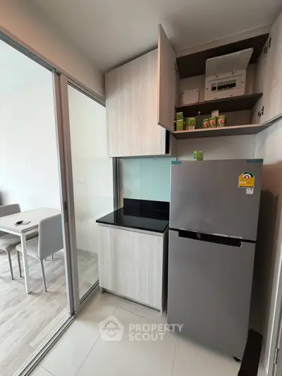 Modern kitchen with sleek cabinetry and stainless steel fridge in a stylish apartment.