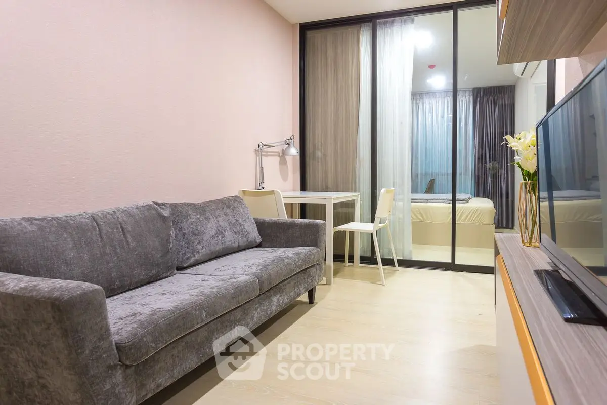 Modern living room with cozy gray sofa and glass partition to bedroom