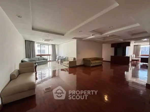 Spacious living room with polished wooden floors and modern furniture in a luxury apartment.