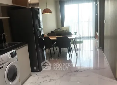 Modern open-plan kitchen and living area with sleek appliances and stylish dining setup.