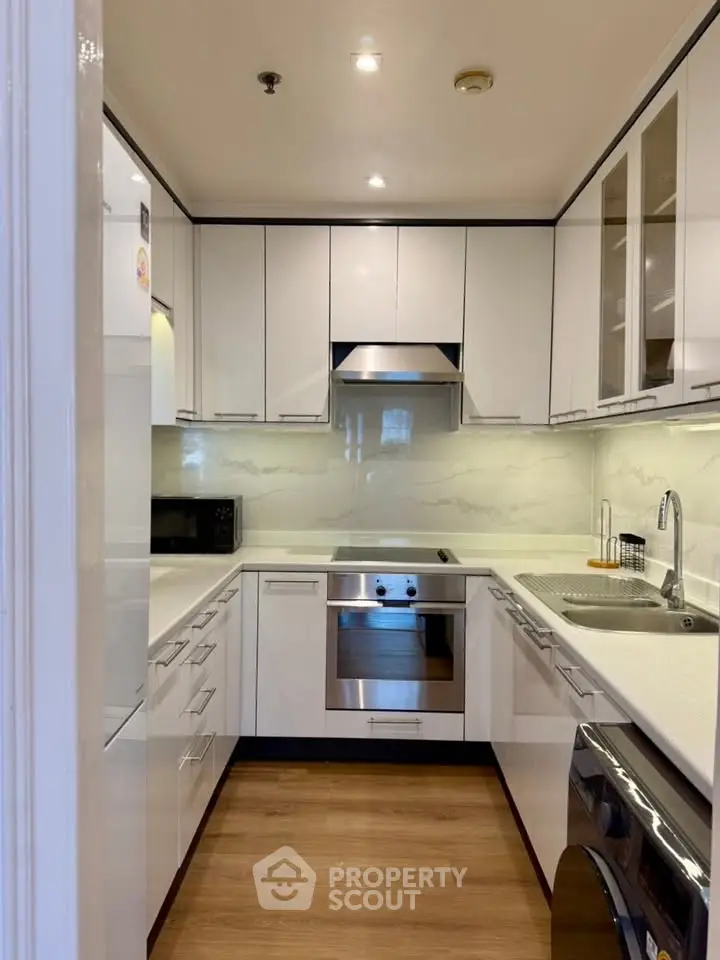 Modern kitchen with sleek white cabinetry and built-in appliances in a compact layout.