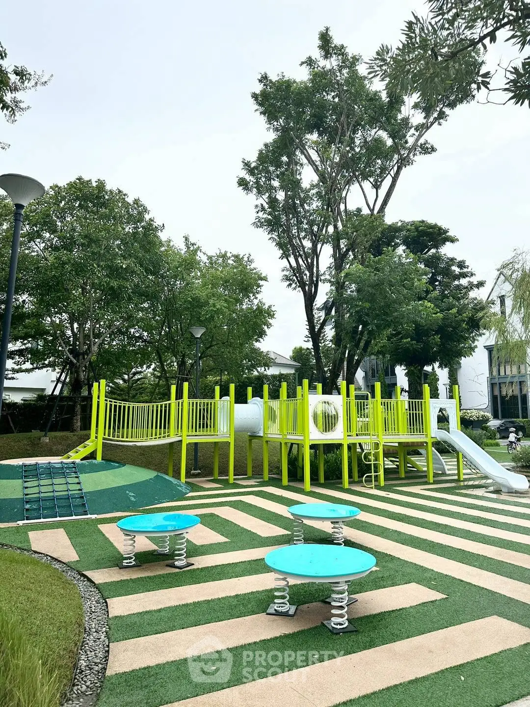 Charming residential playground with vibrant equipment and lush greenery, perfect for family-friendly living.