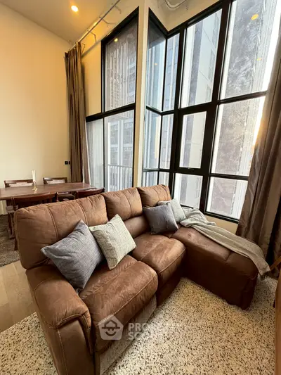 Spacious living room with large windows and cozy brown sofa in modern apartment