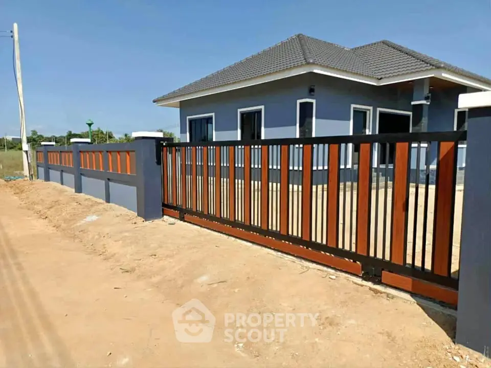 Modern single-story house with stylish fence and spacious yard under clear blue sky.