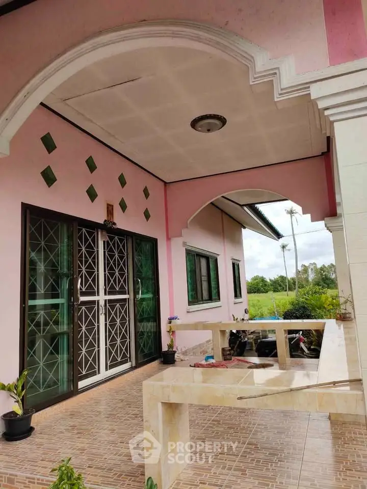 Charming pink exterior of a house with tiled porch and decorative arches.