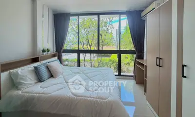Bright and spacious bedroom with large windows and modern furnishings, offering a serene garden view.